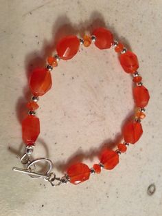 This orange bracelet created by Jewelry By Luet and Co is made of:  orange carnelian gemstones, sterling silver:   beads, toggle clasp and findings.  This bracelet measures 7 1/2 inches. WE OFFER FREE SHIPPING WITHIN THE UNITED STATES. All of our jewelry is unique and custom designed.  We would love to assist you with any custom orders or needs for special occasions! We appreciate you shopping with Jewelry By Luet and Co and hope you will do so often!  See more items from my shop: http://www.ets Orange Bracelet, Orange Carnelian, Gemstone Beads Jewelry, Beaded Jewellery, Bracelet Sterling Silver, Toggle Clasp, Silver Beads, Sterling Silver Bracelets, Custom Orders