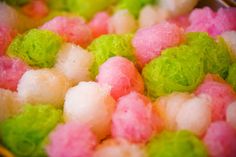 there are many different colored cotton balls in the bowl on the table, including pink and green