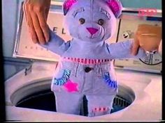 a stuffed animal that is sitting in a washer with its hands on top of it