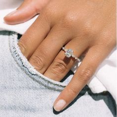 a close up of a person's hand with a diamond ring on their finger