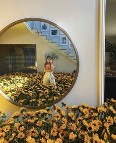 a woman taking a selfie in front of a mirror with sunflowers on the ground