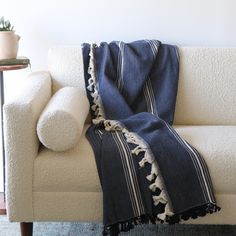 a white couch with a black and white blanket on top of it next to a potted plant