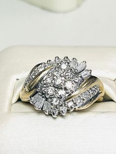 two wedding rings sitting on top of a white cloth covered box, with one diamond set in the middle