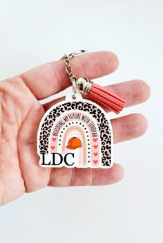 a hand holding a keychain with a design on it