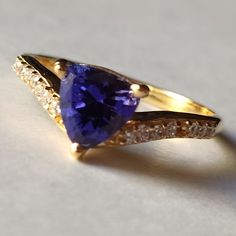 Material  14k Yellow Gold  . Gemstone  Natural Tanzanite  . Gemstone Colour  Blue  . Gemstone Shape  Trillion  . Gemstone Size  6x6MM . birthstone  December  . Cut Grade  Excellent . Style  Art Deco Formal Tanzanite Trillion Cut Ring, Yellow Gold Tanzanite Diamond Ring With Accent Stones, Yellow Gold Tanzanite Rings With Accent Stones, Fine Jewelry Yellow Gold Tanzanite Rings, Tanzanite Trillion Cut Ring For Anniversary, Blue Tanzanite Ring With Trillion Cut, Gold Tanzanite Gemstone Rings, Elegant Tanzanite Trillion Cut Rings, Trillion Cut Tanzanite Ring For Anniversary