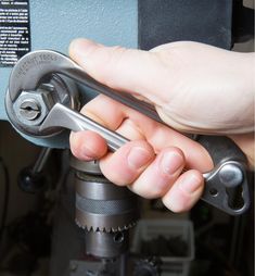 a hand holding a wrench in front of a machine