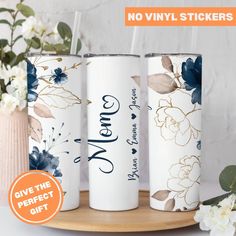 three personalized tumbles with floral designs on them, one is white and the other is blue