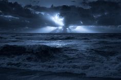 the sun is shining through clouds over the ocean and waves on the beach at night