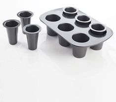 an assortment of cupcake pans on a white table with cups in the middle