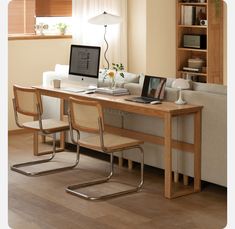 a laptop computer sitting on top of a wooden table in front of a white couch