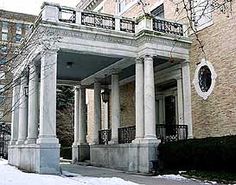 an old building with columns and a clock on the front porch is covered in snow