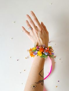 a woman's arm with flowers on it and a ring around her wrist that has confetti all over it