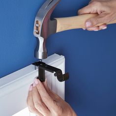 two hands are using a hammer to fix a radiator in a room with blue walls