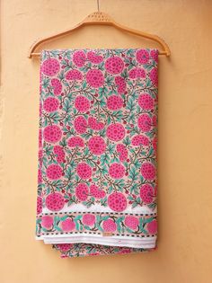 a pink and blue towel hanging on a wooden hanger next to a yellow wall