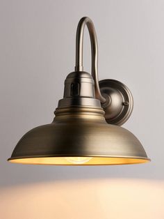 an antique brass wall light with a white shade