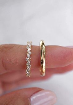 a woman's hand holding a gold ring with three stones on it and one diamond in the middle