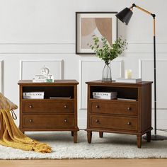 two nightstands side by side with books and magazines on them, next to a lamp