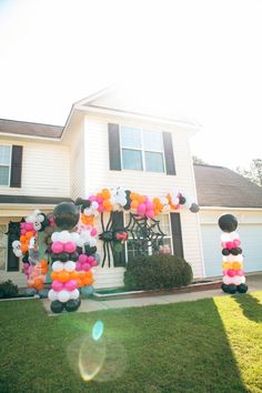 an outside view of a house with balloons and decorations on the front lawn, along with a large balloon arch