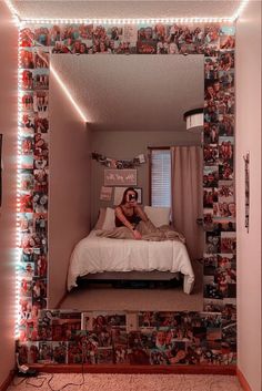 a woman sitting on top of a bed in front of a mirror with lights above it