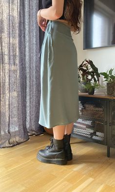 a woman standing on top of a wooden floor in front of a window wearing black boots