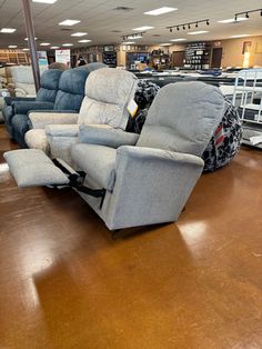 two recliners are sitting in the middle of a store floor with other furniture