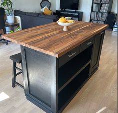 a kitchen island with two stools and a bowl of fruit on the counter top