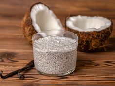 a glass filled with oatmeal next to a coconut on a wooden table