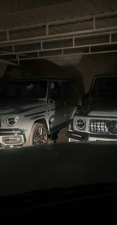 two jeeps parked in a parking garage at night with their lights on and the headlights turned on