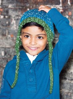 a young boy wearing a blue shirt and green knitted hat with sequins