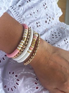 Are you searching for the trendy pink beaded boho bracelets to elevate your accessory game? Look no further! Our stack of 5 bracelets offers versatility and endless possibilities, allowing you to mix and match to your preference. Whether you're aiming for a layered and trendy look or a single statement piece, these bracelets have got you covered. Check out our beautiful stack of 5 beaded stretch bracelets for women, made with real gold plated beads, pink and white heishi beads. Handcrafted with love and a keen attention to detail, our beaded boho bracelets are designed to exceed your expectations. Crafted with high-quality materials, these bracelets capture the essence of bohemian style, perfect for those seeking a free-spirited, artsy vibe. The golden beads boast a touch of elegance and o Heishi Bead Bracelet Patterns, Gold Stackable Friendship Bracelets For Beach, Gold Heishi Beaded Bracelets For Vacation, Stackable Beaded Bracelets For Beach, Pink Stackable Beaded Bracelets For Summer, Stackable Pink Beaded Bracelets For Summer, Gold Beaded Bracelets With Letter Beads For Vacation, Letter Beads Bracelets For Vacation, Vacation Letter Beads Bracelet