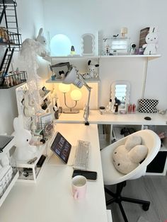 a white desk topped with a laptop computer next to a stuffed animal in a chair