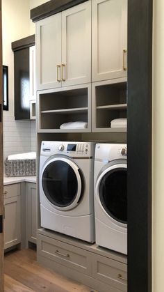 a washer and dryer in a room with white cabinets on either side of the door