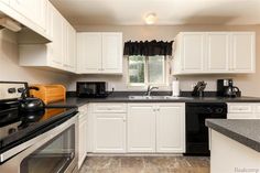 a kitchen with white cabinets and black counter tops