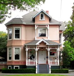 a large pink house with white trim on the front porch and two story entryway