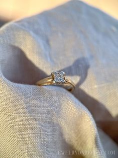 a diamond ring sitting on top of a white cloth covered in light colored linens