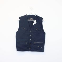 SKU - DM4998  Vintage BNWT Deadstock Working Brand vest in navy. Best fits M DETAILS:  ▫️ Front pockets ▫️ Button up   👕 Fits like a ~ M ▫️ Label states ~ M ▫️ Pit to Pit ~ 18.5" ▫️ Length ~ 22" ▫️ Pit to Cuff ~ N/A   👇 If any defect is found and it is not included in the provided photos, it will be listed below. ▫️    🧺 All items are professionally washed and ironed before photos are taken and then sold.    ✅ If the item is listed, it is available    ❌ Disclaimer: Like all vintage items they Casual Workwear Vest With Pockets, Cotton Vest With Pockets For Workwear, Sleeveless Outerwear With Side Pockets For Work, Cotton Workwear Vest With Pockets, Cotton Work Vest With Pockets, Workwear Vest With Pockets, Utility Denim Vest With Pockets For Work, Cotton Vest With Snap Buttons For Work, Utility Sleeveless Tops With Pockets