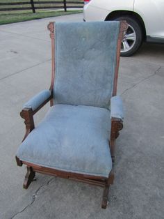 a blue chair sitting on the sidewalk next to a white car