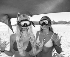 two women wearing goggles and bikinis on the beach