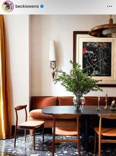 a dining room table with four chairs and a potted plant in the center, next to a couch