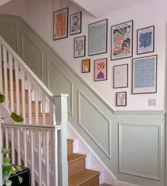 a staircase with pictures on the wall above it and a basket under the banister