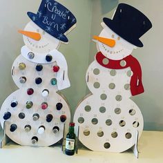 two snowmen made out of wine bottle caps and magnets, one with a top hat