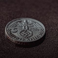 a close up of a coin on a black surface with the number five in it