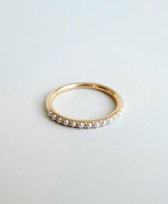 a yellow gold ring with five small white pearls on it's side, sitting on a white surface