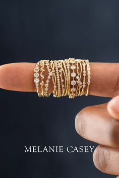 a woman's hand holding up a stack of gold rings with diamonds on them