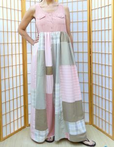 a woman standing in front of an open door wearing a pink and grey dress with squares on it