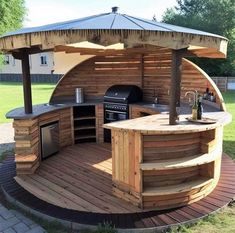 an outdoor kitchen is built into the side of a wooden structure with a grill and sink