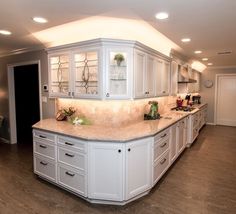 a large kitchen with white cabinets and marble counter tops