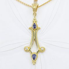 This 18K gold pendant beautifully combines sumptuous tanzanites with diamond accents to create an elegant, eye-catching piece of jewelry. Crafted with an elegant simplicity, this pendant will take your look from everyday to extraordinary. 18KY granulated pendant set with 0.54cttw of beautiful pear-shaped tanzanites and 0.06cttw of VS/G-H diamonds (chain sold separately)Dimensions: 2-1/4" x 3/4" (57mm x 19mm) including bail Gold Tanzanite Pendant Jewelry, Elegant Tanzanite Oval Pendant Jewelry, Elegant Tanzanite Jewelry Hallmarked, Elegant Hallmarked Tanzanite Jewelry, Yellow Gold Tanzanite Pendant Necklace, Gold Tanzanite Pendant Necklace, Elegant Gold Tanzanite Necklace, Elegant Yellow Gold Tanzanite Necklaces, Elegant Yellow Gold Tanzanite Necklace