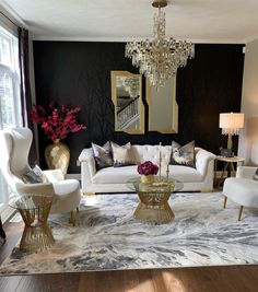 a living room filled with white furniture and a chandelier hanging from the ceiling