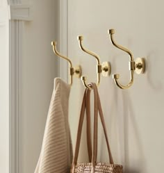 three hooks on the wall holding two purses